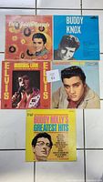 Top view of five vinyl record covers featuring Elvis Presley, Buddy Knox, and Buddy Holly, arranged in a grid on a tiled floor.