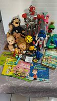Full view of assorted toys including dolls, robot, plush, books, and other figurines