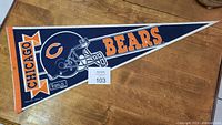 Photo of a vintage Chicago Bears NFL football pennant with blue, orange, and white team colors and helmet logo.