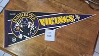 Vintage triangular NFL Minnesota Vikings football pennant showing a cartoon football player holding a ball and team name/logo in yellow and purple colors