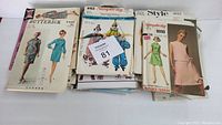 Top view of assorted vintage sewing patterns in paper envelopes showing various brands and designs.