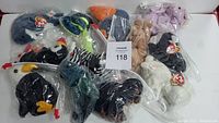 Photo of multiple vintage Ty Beanie Babies, each sealed in clear plastic bags laid out on a white surface showing various animal characters.