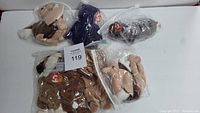 Six Ty Beanie Babies plush toys individually bagged on white surface.