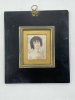 Front view of the entire framed miniature portrait with the black backing and gold-toned inner frame.