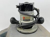 Front and side view of the Black & Decker Commercial Duty router with power cord wrapped around handles showing the label and general condition.
