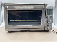 Front view of Breville convection toaster oven showing the glass door and front handle with control panel on right side.