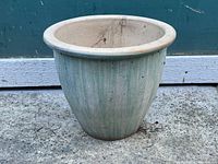 Side view of a vintage ceramic pot showing vertical ridges and off-white glaze with wear.