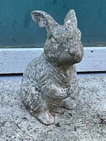 Front view of the concrete bunny showing the detailed face and posture, with visible weathering.