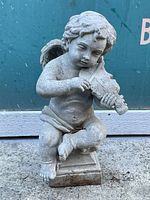 Front view of the concrete cherub garden decoration showing detailed features and violin.
