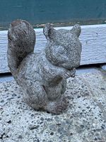 Front right side view of concrete squirrel decoration showing detailed facial features and tail.