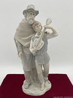 Front view of Lladro figurine showing the older man with hat and cloak behind the boy playing guitar