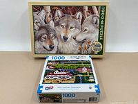 Two boxed puzzles shown side by side with box art visible: Cobble Hill wolf puzzle and Sure-Lox Hometown Collection farm puzzle.