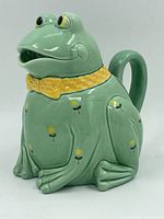 Front view of vintage Otagiri frog pot with green glaze, yellow collar, and floral decoration.