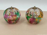 Pair of spherical art glass oil lamps with multicolored swirled patterns showing overall appearance.