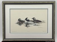 Framed print depicting three ducks floating on water with the title and numbering visible.