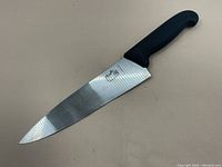 Full view of a Victorinox kitchen chef knife with stainless steel blade and black handle.