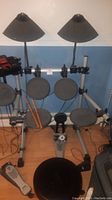 Full front view showing entire drum kit on rack with stool and sticks