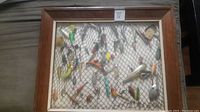 Overall view of the framed fishing lure collection showing various colorful lures and the wooden frame.
