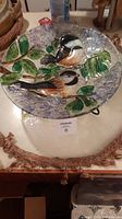 Top view of decorative glass bowl with painted chickadee birds and green leaves on a textured floral background.