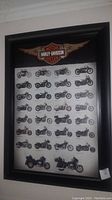 Full view of black framed Harley-Davidson motorcycle history picture with multiple motorcycles shown and the Harley-Davidson logo.