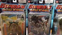 Four Gundam Battle Scarred action figures in original sealed blister packaging. Figures include Dragon Gundam, Burning Gundam, Shining Gundam, Wing Gundam Zero Custom. Accessories and battle damage effects included in packaging.