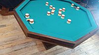Octagonal bumper pool table top with green felt surface, wooden bumpers and balls scattered