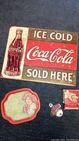 Photo of the Coca-Cola tin sign, serving tray, bottle opener, and original box arranged on carpet