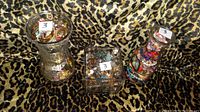 Three glass jars filled with various vintage jewelry pieces displayed on leopard print fabric.