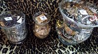 Three glass jars filled with assorted vintage jewelry on leopard print background.