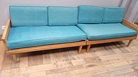 Front view of two aqua upholstered sofas side by side showing wood frames and cushions