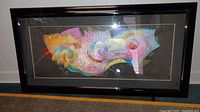 Full view of the framed abstract painting showing the entire piece within the black frame, including matting.