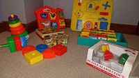 Wide view of the entire lot showing various wooden educational toys including shape sorters, puzzles, stacking rings, and boxed puzzle alarm clock.