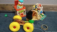Image of all three vintage Fisher Price toys: Jack in the Box clown toy, wobble dog pull toy, and merry go round Ferris wheel toy.