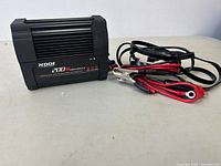 NDDI 200W power inverter with cables and clamps attached, shown on flat surface.