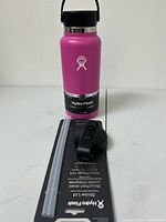 Pink 32 oz Hydro Flask bottle with black lid on top, two clear straws and black straw lid in front on a Hydro Flask tag.