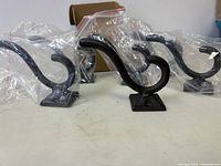 Six cast iron hooks in original packaging and box, showing the complete set.
