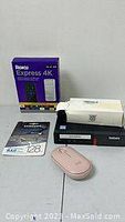 Overview of the lot including Roku Express 4K box, Samsung 128GB microSD card package, Lenovo ThinkCentre desktop, and pink Logitech wireless mouse on white surface.