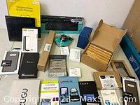 Overview of all electronic accessories including screen protectors, phone cases in boxes, keyboard, mouse, and other items on table.