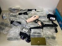 Lot overview showing multiple bubble-wrapped sunglasses, an unwrapped black sunglasses pair, a green wallet, and a pink Silk & Co hair dryer with black cord.
