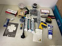 Overview of all items including tubes of adhesive sealant, fishing accessories, duct tape, and hardware.
