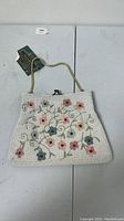 Front view showing overall white beaded purse with mulicolor floral design in pink, blue and beige shades with green bead vines.