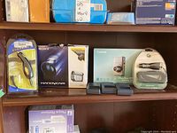 Sony Handycam box, Canon PowerShot box, battery chargers and accessories displayed on wooden shelf