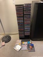 Front view of two vertical columns of CDs stacked in black plastic tower with a few loose CDs on floor.