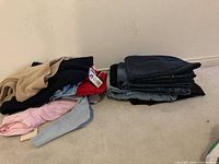 Pile of assorted ladies shirts in different colors and textures on carpet