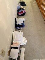 View down a hallway showing multiple stacks of folded clothing including white shirts, black shirts, and other assorted items.