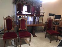 Set of six oak dining chairs: four side chairs and two armchairs placed on and around a wooden table