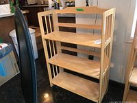 Full view of wooden shelving unit with three shelves and vertical slat sides.