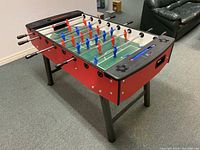 Angled full view showing red side panels, black legs and playing field