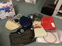 Overview showing all eight items including various handbags, wallets, and branded gift bags arranged on carpet.