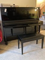 Front view of Samick upright piano with closed fallboard and bench in front